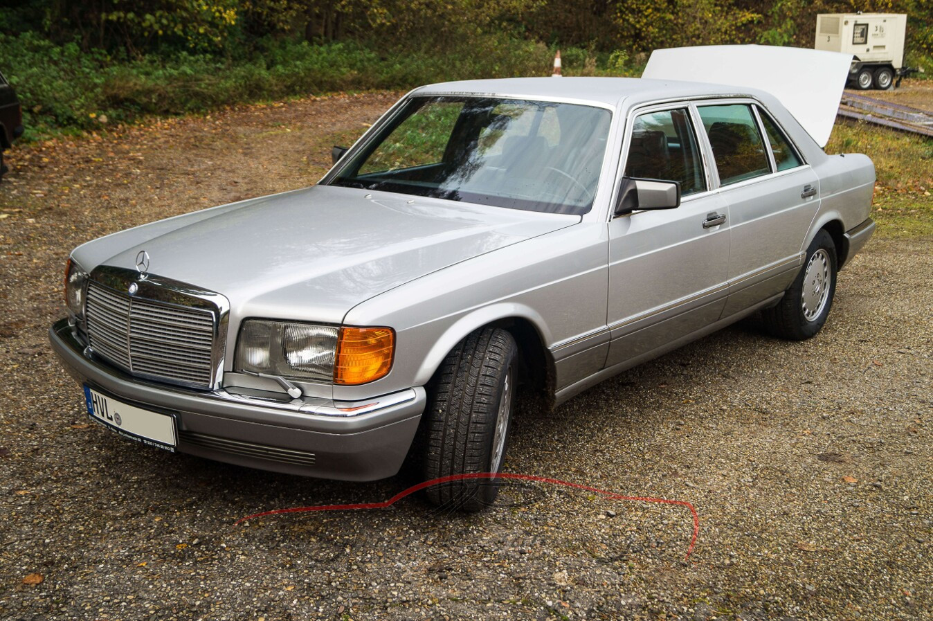 Ein silberner Mercedes-Benz mit geöffneter Kofferraumklappe steht auf einem gepflasterten Platz.